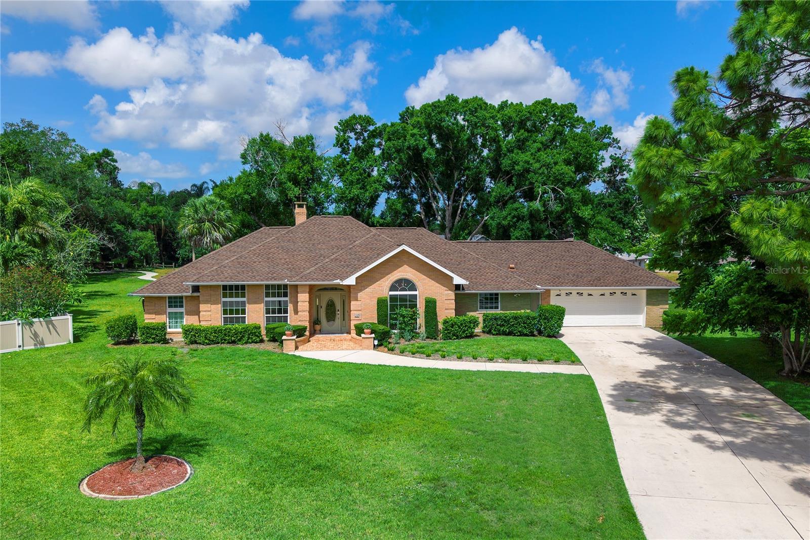 Single-story brick house with an arched front window, landscaped lawn, and attached garage.