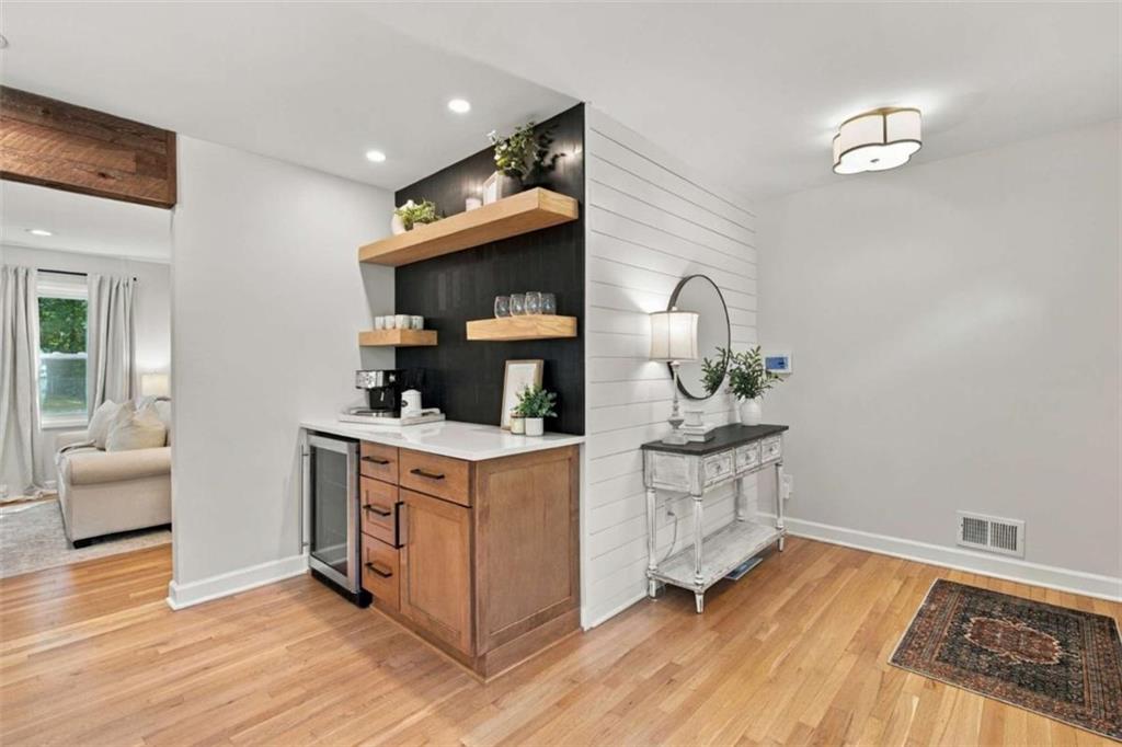 Built-in beverage bar with wood cabinetry, floating shelves, and a compact under-counter refrigerator.