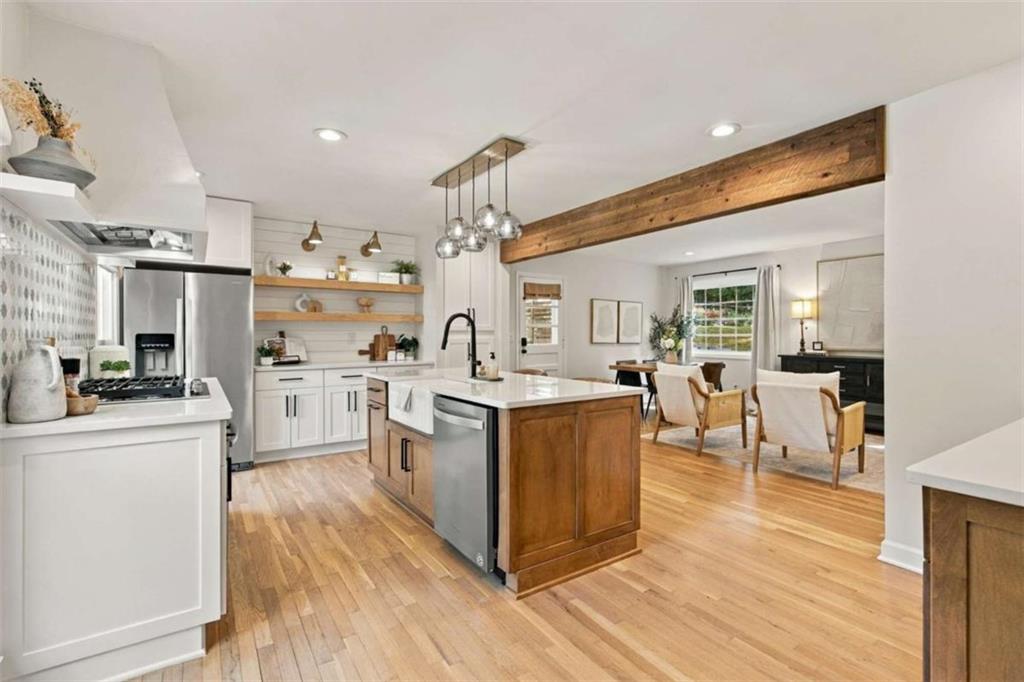 Kitchen with wood-paneled island and exposed beam opening to a dining area.