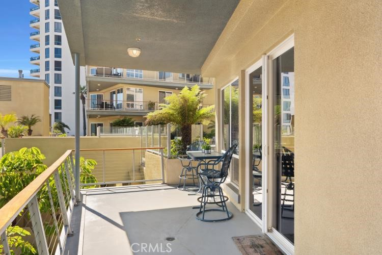 Furnished apartment balcony overlooking a landscaped courtyard and neighboring buildings.