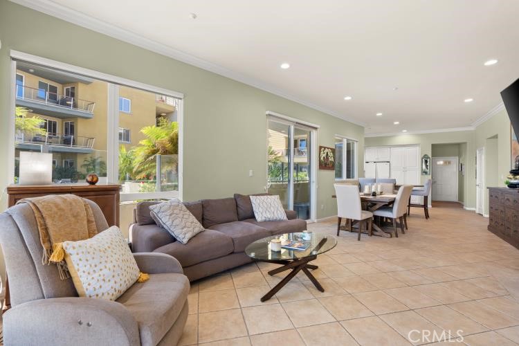 Living room with a gray sofa and large windows overlooking a neighboring building and greenery.