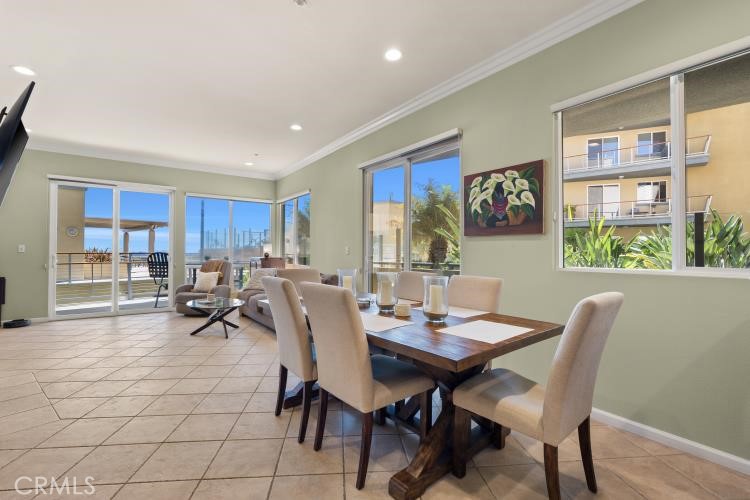 Dining area with a dark wood table and large windows overlooking the ocean and city skyline.