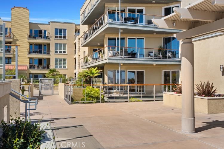 Condominium courtyard with stacked balconies, a paved walkway, and landscaped planters.