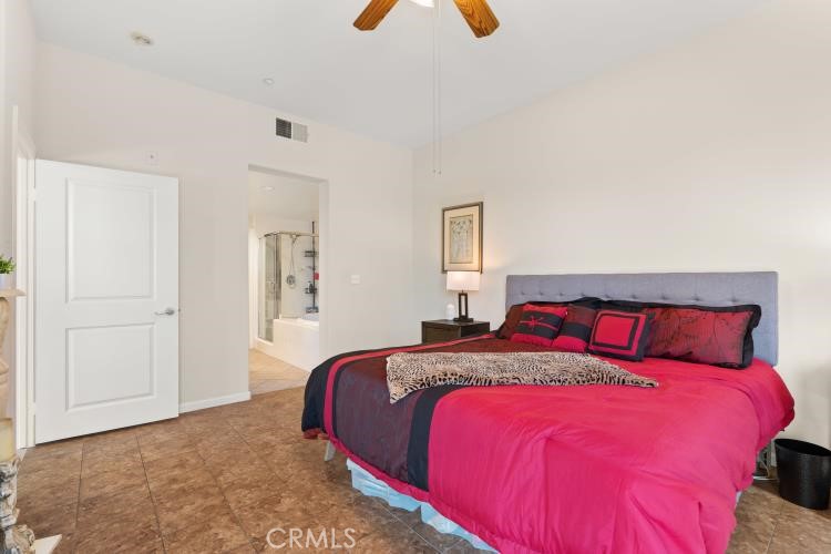 Bedroom with a large fuchsia-covered bed and an open door to a bathroom shower.