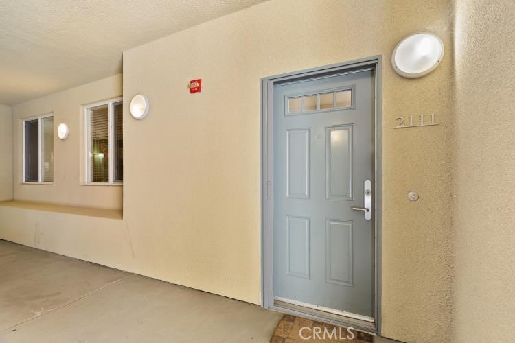 Condominium entry 2111 with a pale blue paneled door and beige stucco corridor.