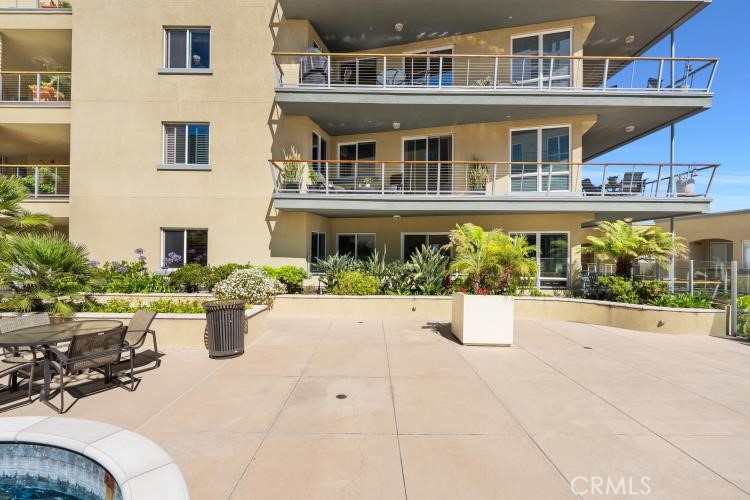 Condominium exterior with stacked balconies overlooking a landscaped terrace and pool edge.