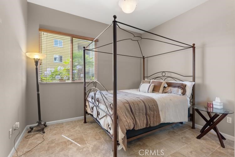 Bedroom with a dark metal four-poster bed, neutral bedding, and a window with blinds.