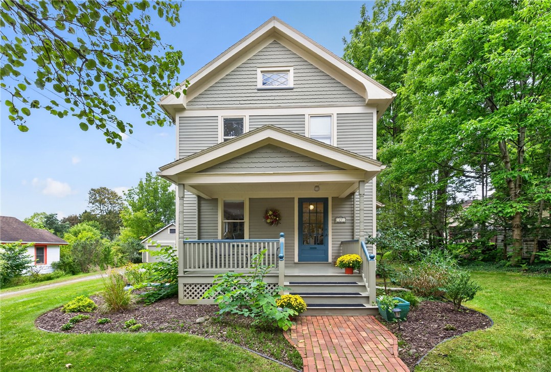 Gray two-story house with a covered porch, blue front door, and brick walkway.