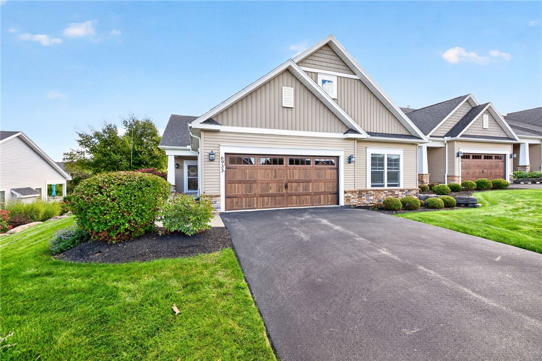 Suburban home's front exterior with a double garage, landscaped lawn, and wide asphalt driveway.