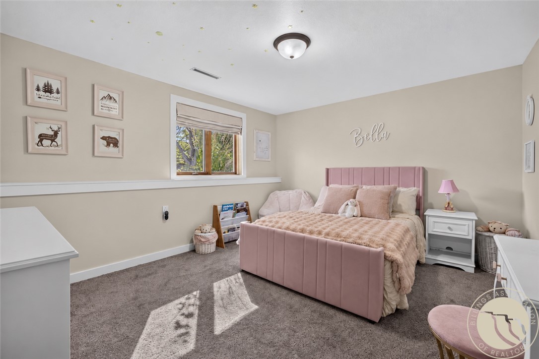 Bedroom with a pink upholstered bed, plush bedding, and sunlight through a small window.