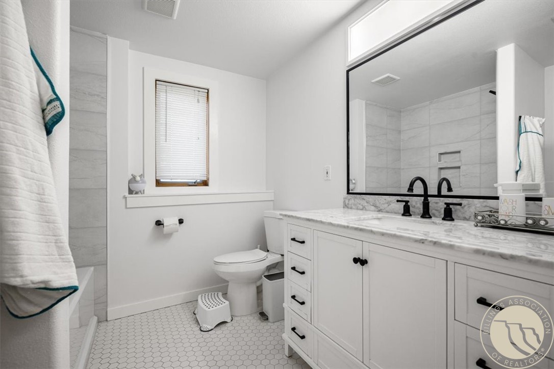 Bathroom with a white vanity, large black-framed mirror, and hexagonal tile floor.