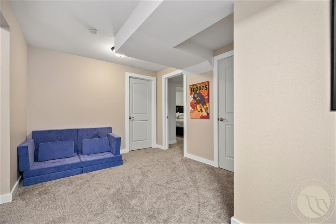 Carpeted sitting area with a blue loveseat, white doors, and a glimpse into a bedroom.