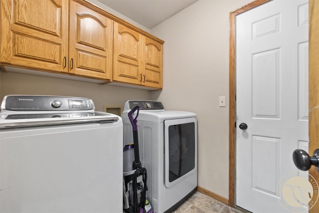 Laundry room with a washer, dryer, and honey-colored wooden cabinets.