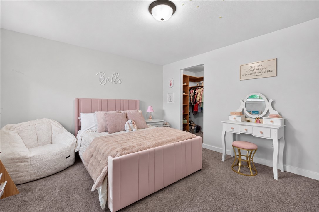 Bedroom with a pink upholstered bed, white vanity, and open closet.