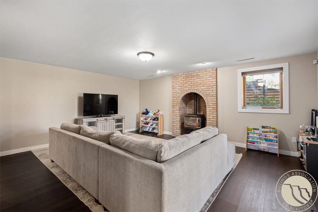 Living room with a gray sectional sofa facing a brick fireplace and wood stove.