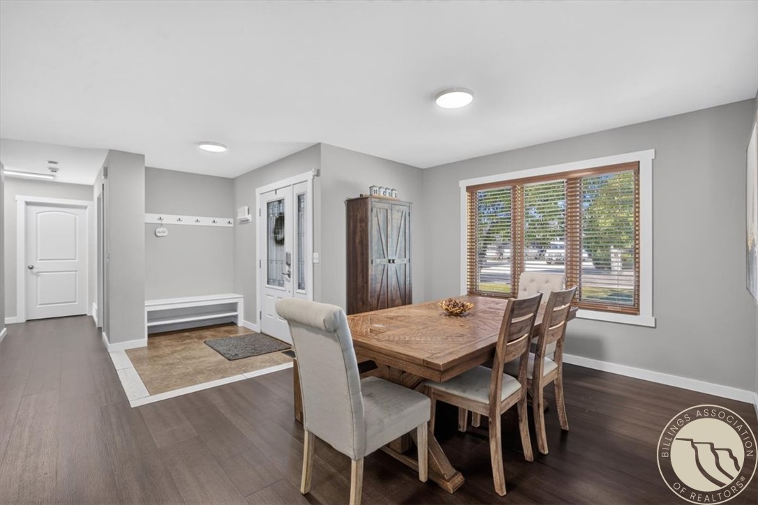 Dining room with a large wooden table beside a bright window and an adjoining entry bench.