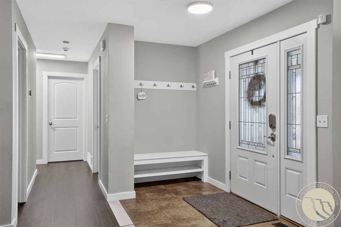 Entryway with a leaded-glass front door, built-in bench, coat hooks, and tile floor.