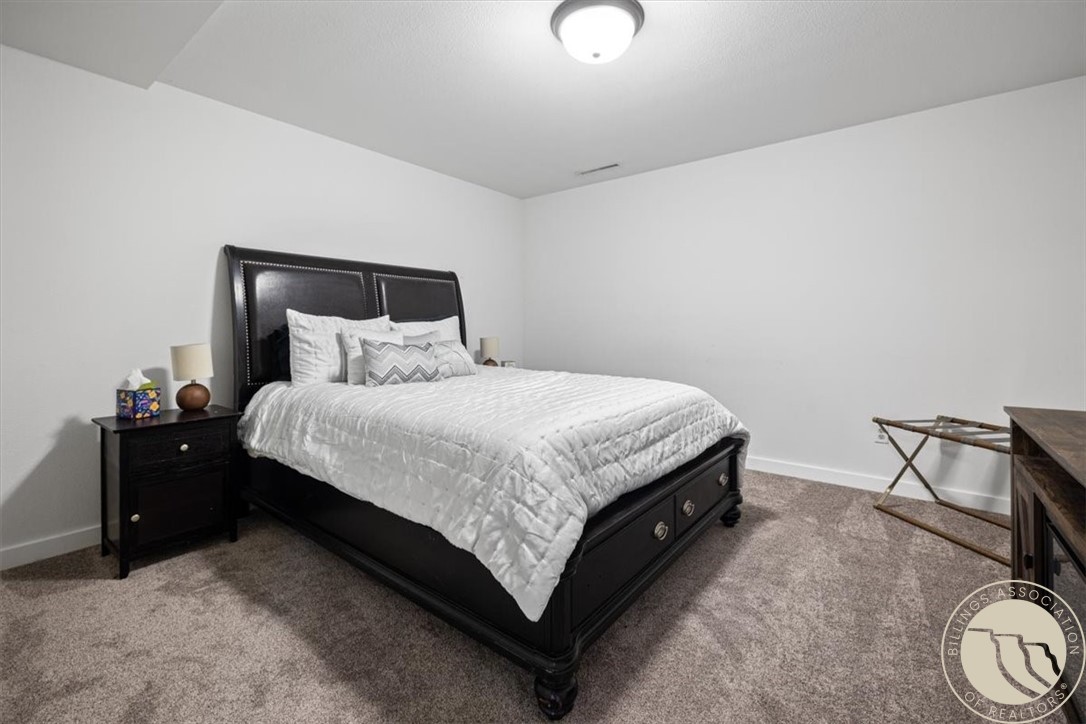 Bedroom with a dark wood bed, white bedding, and gray carpet.