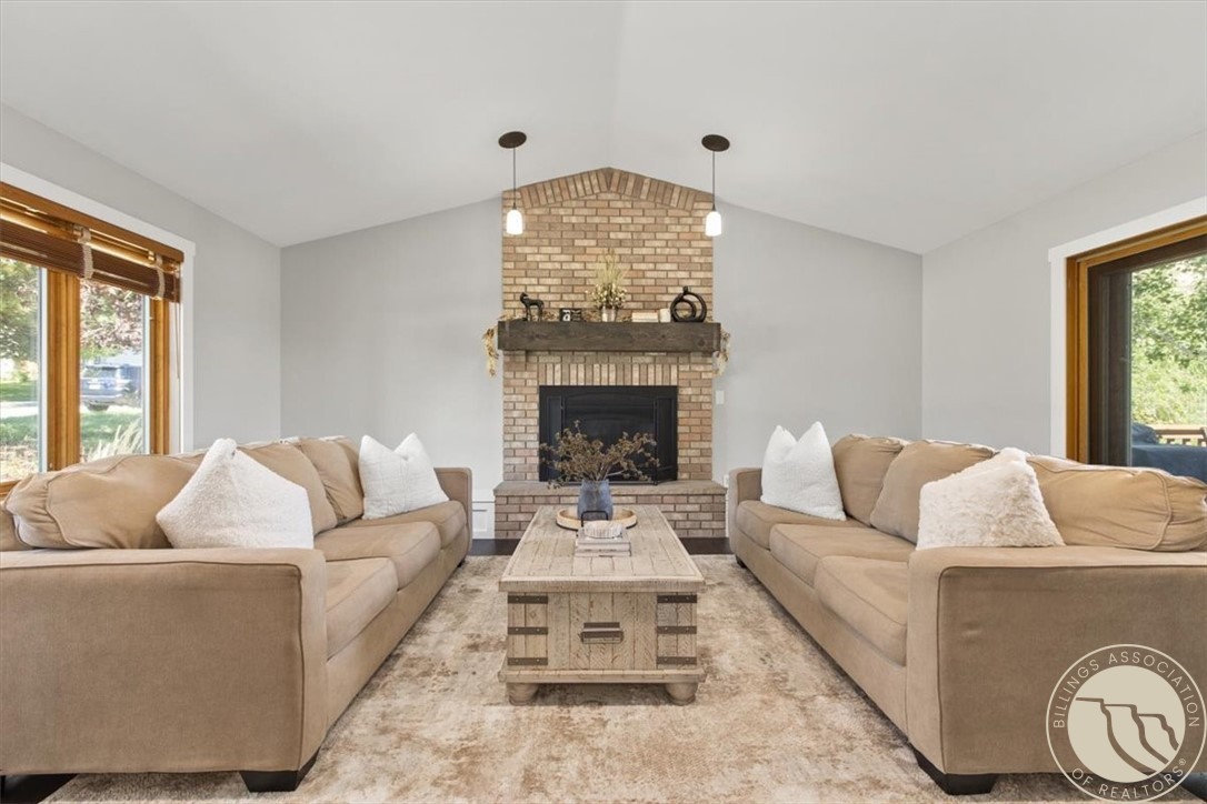Living room with beige sofas, a brick fireplace, and a light wood coffee table.