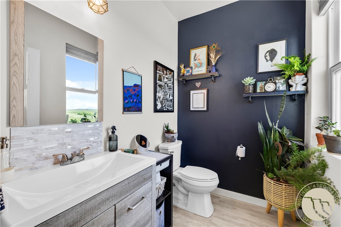 Bathroom with a gray vanity, navy accent wall, floating shelves, and plants.
