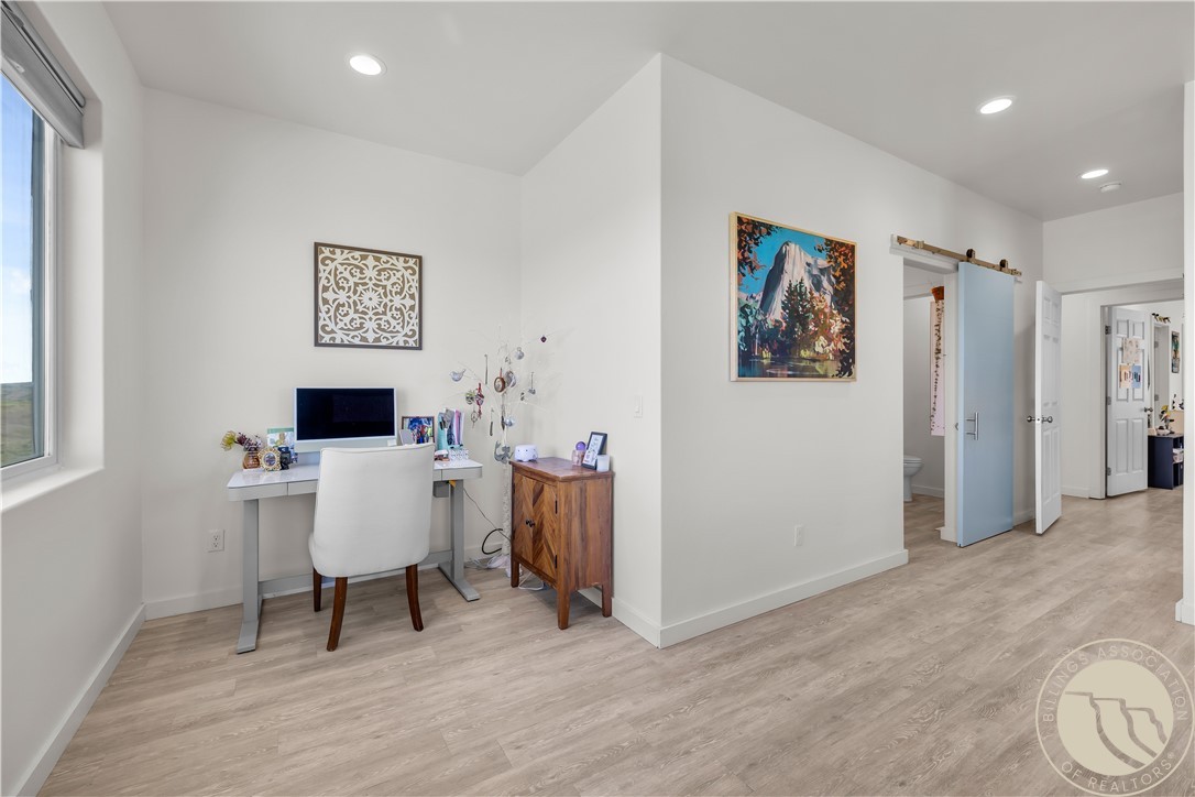 Office nook with a desk and white chair beside a hallway and partially open bathroom door.