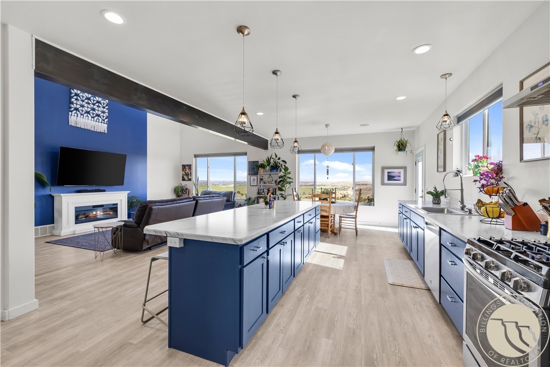 Open kitchen with blue cabinetry, a large island, and adjoining living and dining areas.