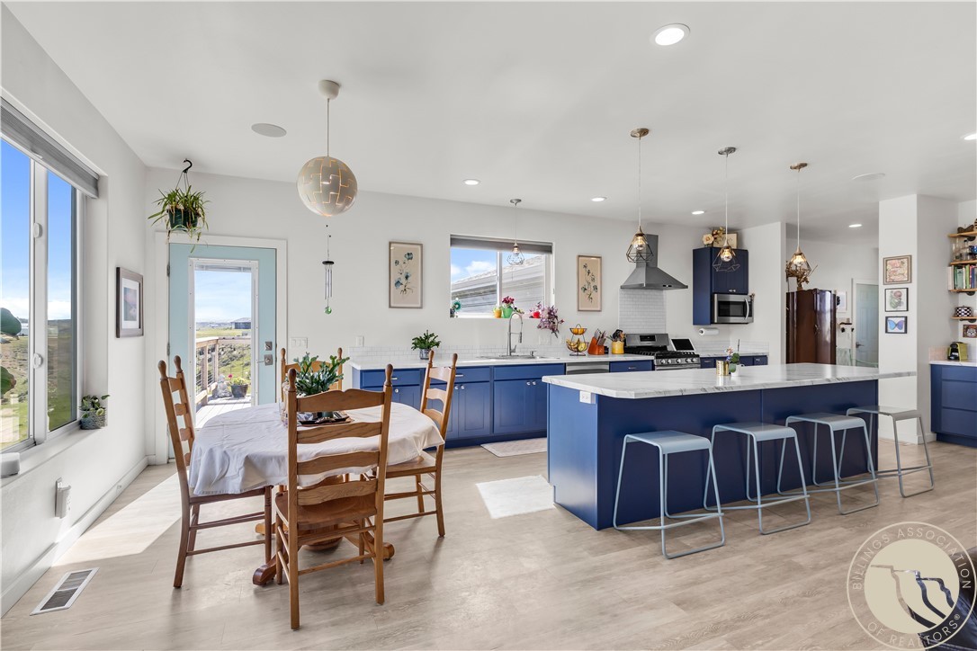 Open kitchen and dining area with blue cabinets, a large island, and wood dining table.