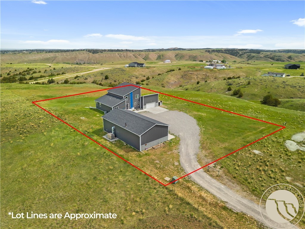 Aerial view of rural property outlined in red, with a house, outbuilding, and gravel drive.