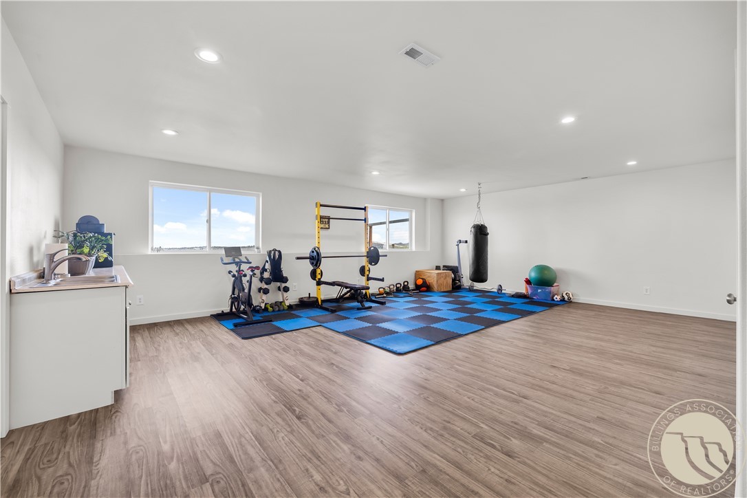 Spacious home gym with weight equipment, a punching bag, and blue-and-black floor mats.