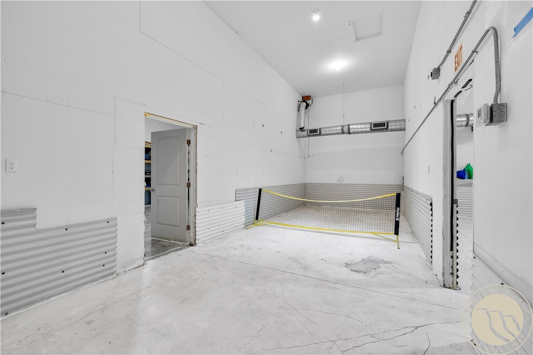 Indoor recreation room with a net across the far end and corrugated lower wall panels.