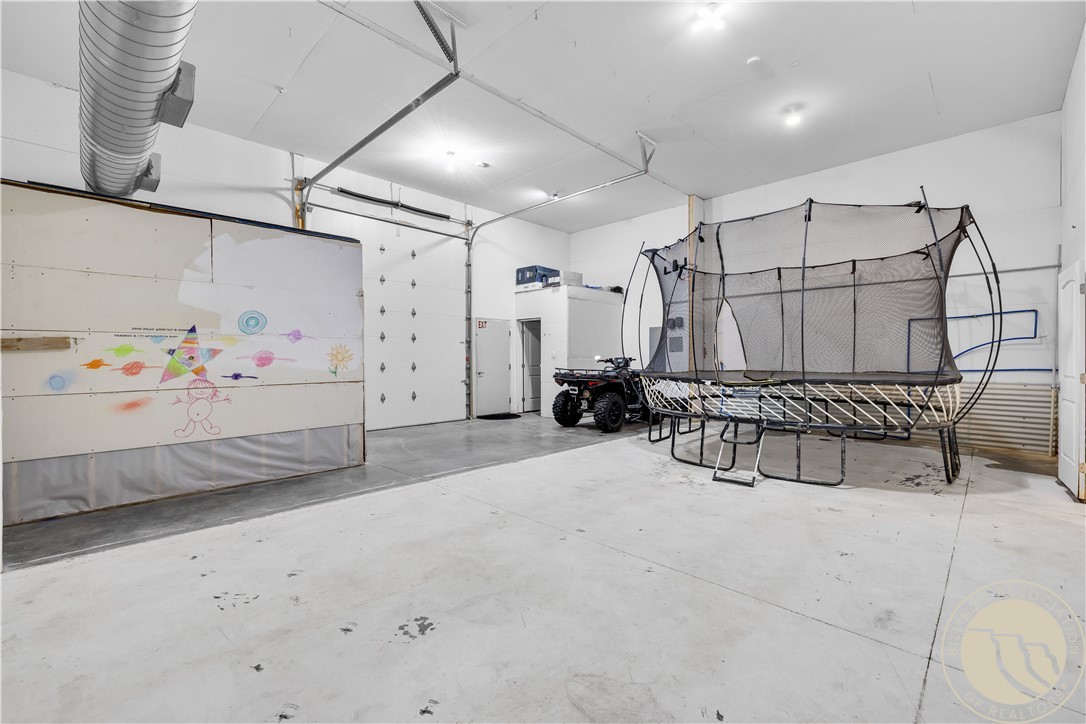 Large garage with a trampoline enclosure, an ATV, and children’s drawings on the garage door.