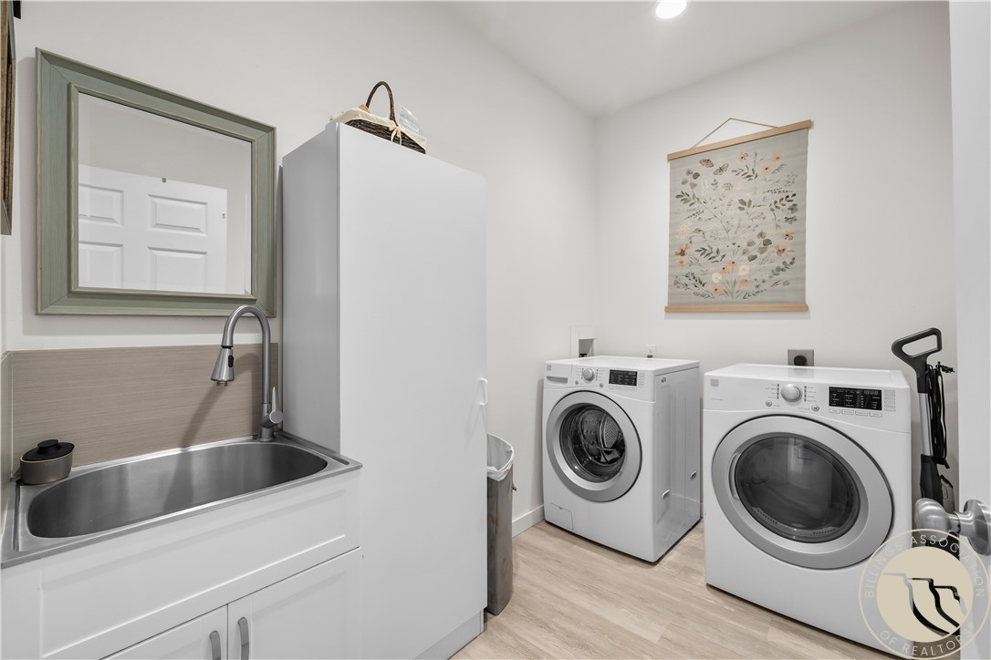 Laundry room with a utility sink, tall storage cabinet, and front-loading washer and dryer.