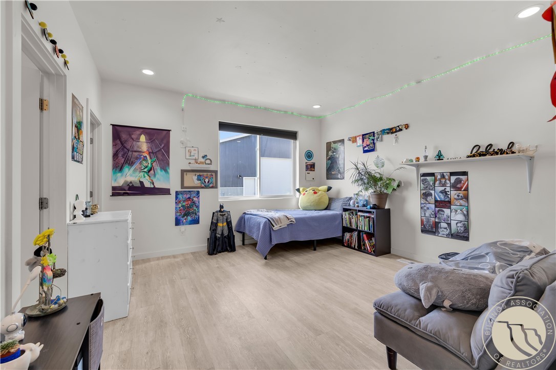 Bedroom with a bed, gray sofa, colorful posters, collectibles, and green LED lighting.