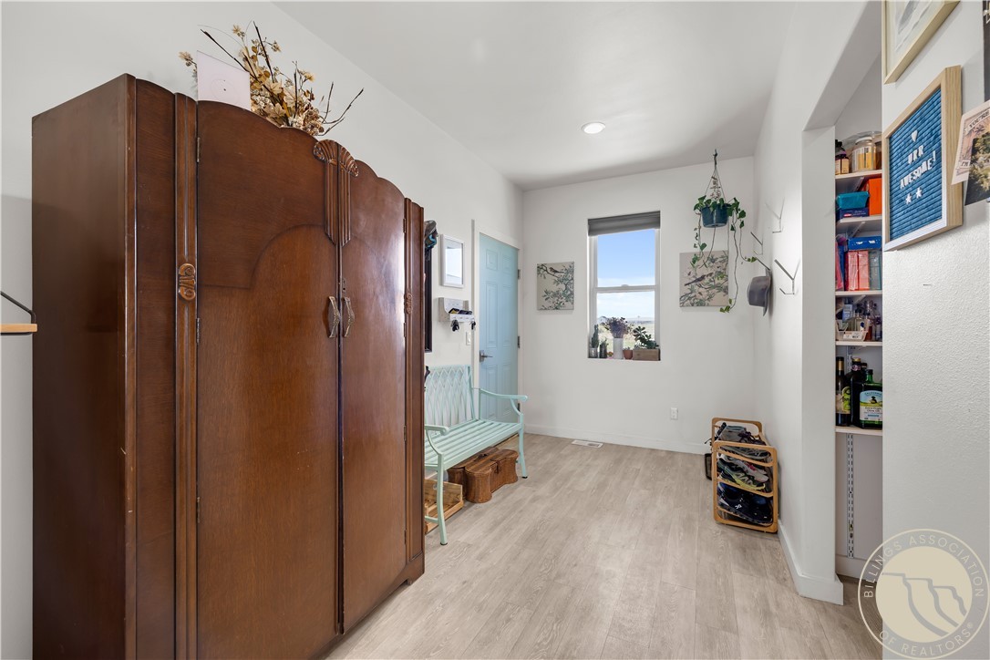 Entryway with a large antique wooden wardrobe, mint-green bench, window, and shoe storage.