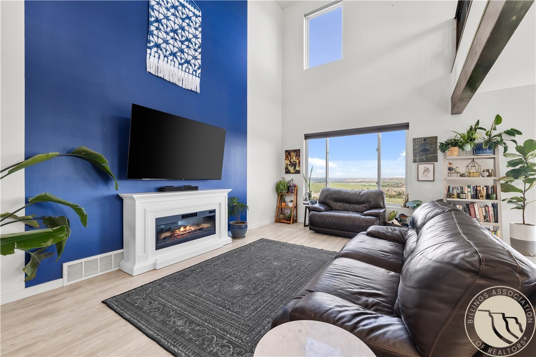 Double-height living room with a blue accent wall, fireplace, leather sofas, and large windows.