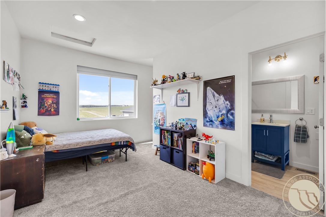 Bedroom with a bed, toy-filled shelves, and a window overlooking open fields.