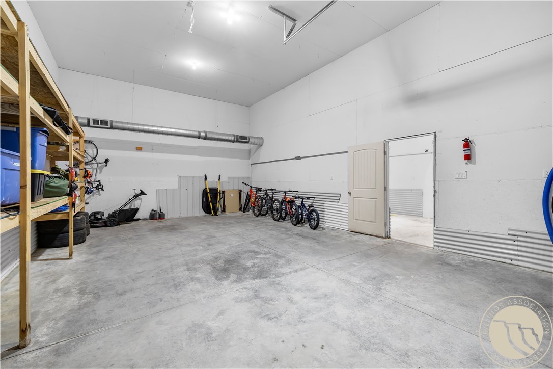 Spacious garage with concrete floor, wooden storage shelves, bicycles, and an open doorway.