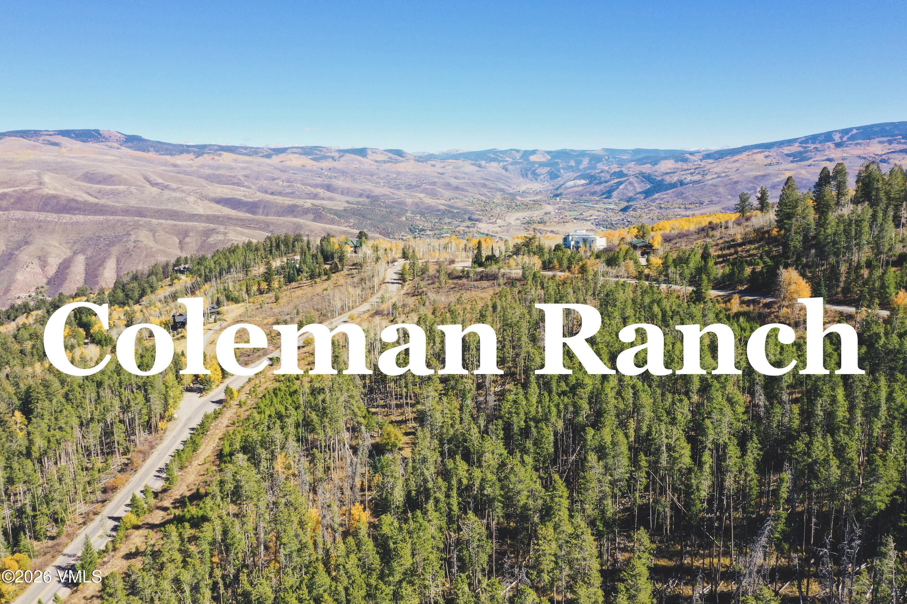 Coleman Ranch aerial view, with forested hillsides, a winding road, and a mountain valley.