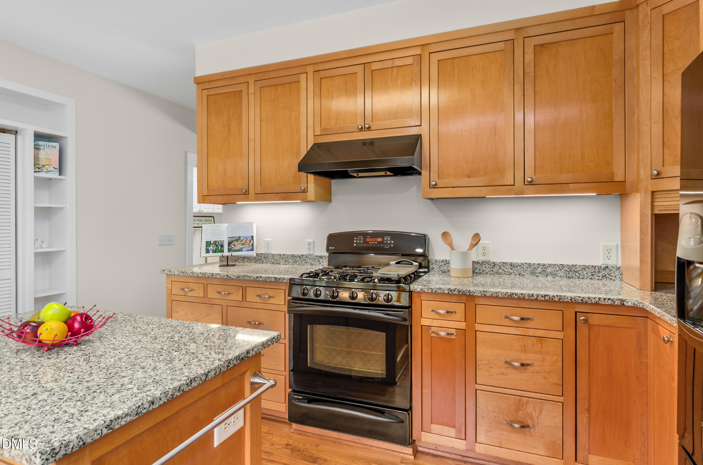 Kitchen with maple cabinets, granite counters, and a black gas range.