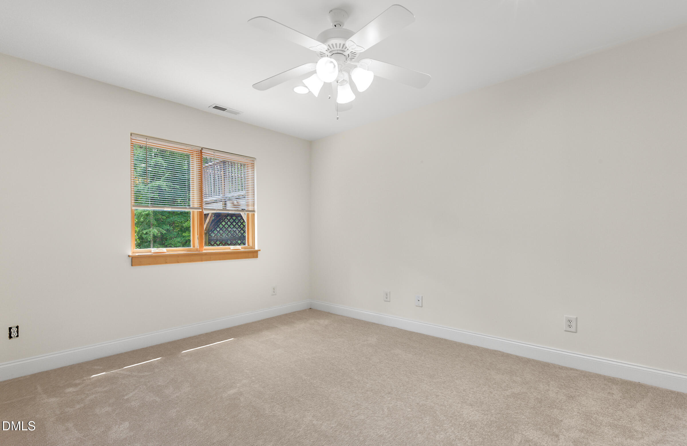 Empty carpeted bedroom with a wood-trimmed window and ceiling fan.
