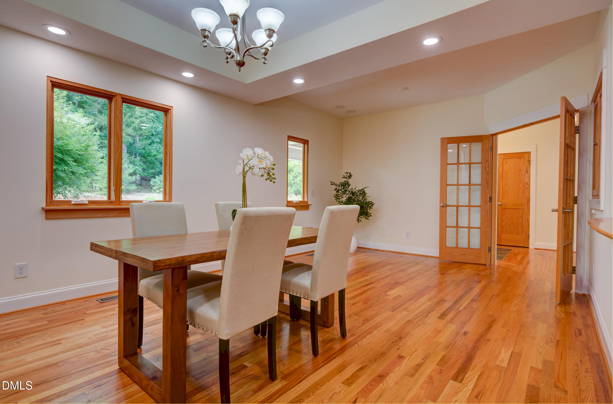 Dining room with a wooden table, hardwood floors, tray ceiling, and French doors.
