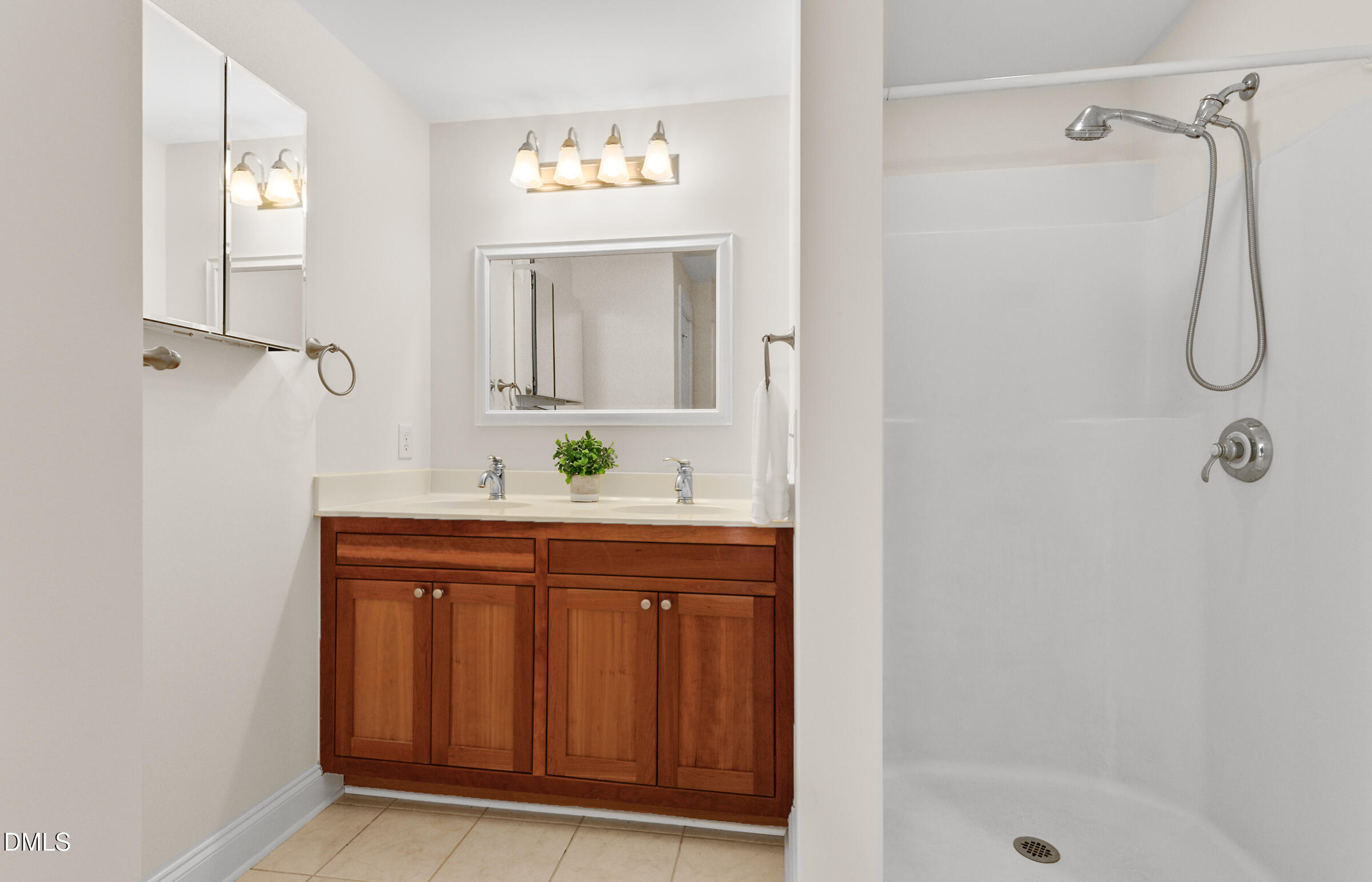 Bathroom with a double-sink wood vanity beside a white walk-in shower.