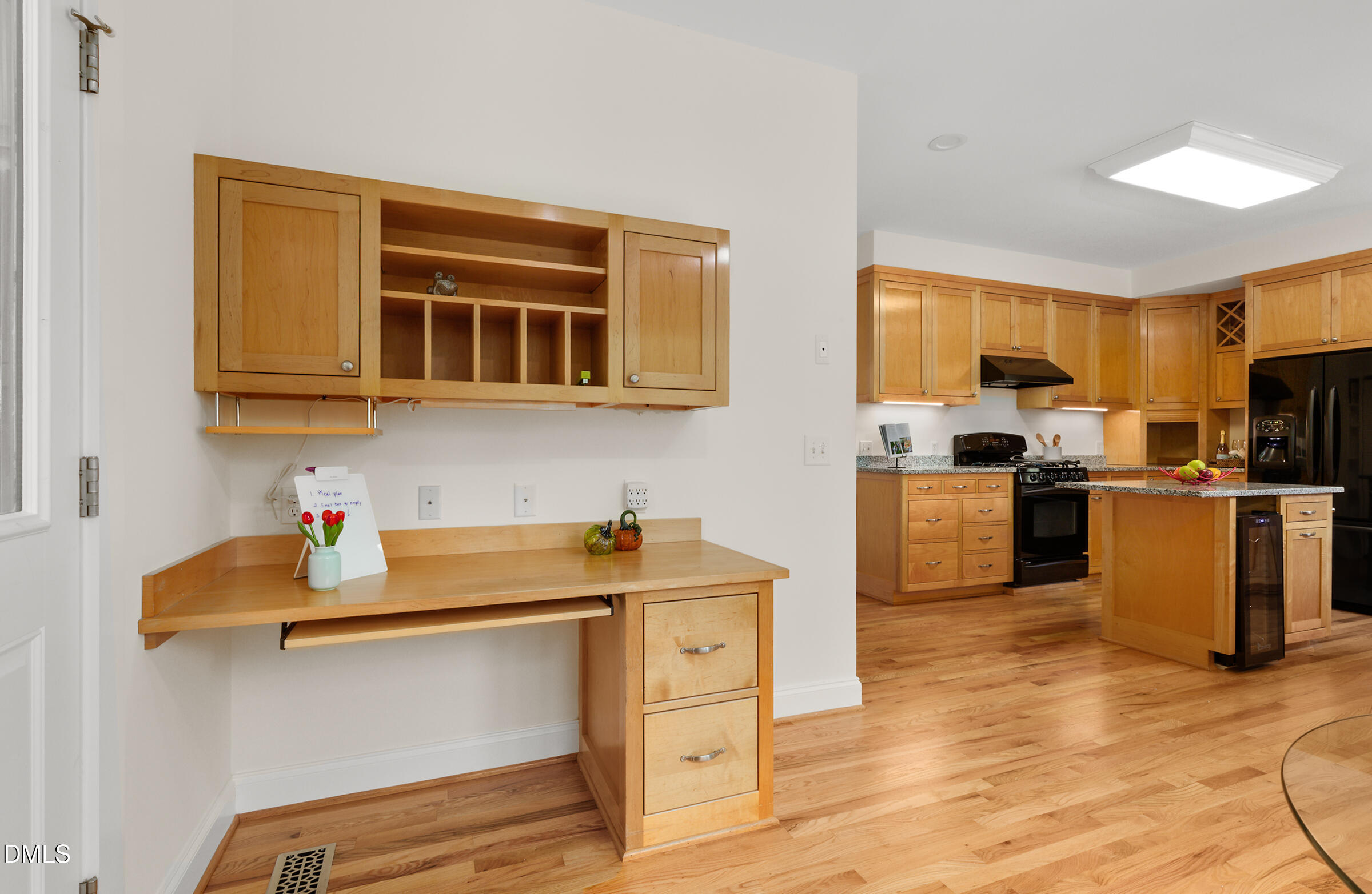 Kitchen with warm wood cabinets, granite counters, black appliances, and a built-in desk nook.