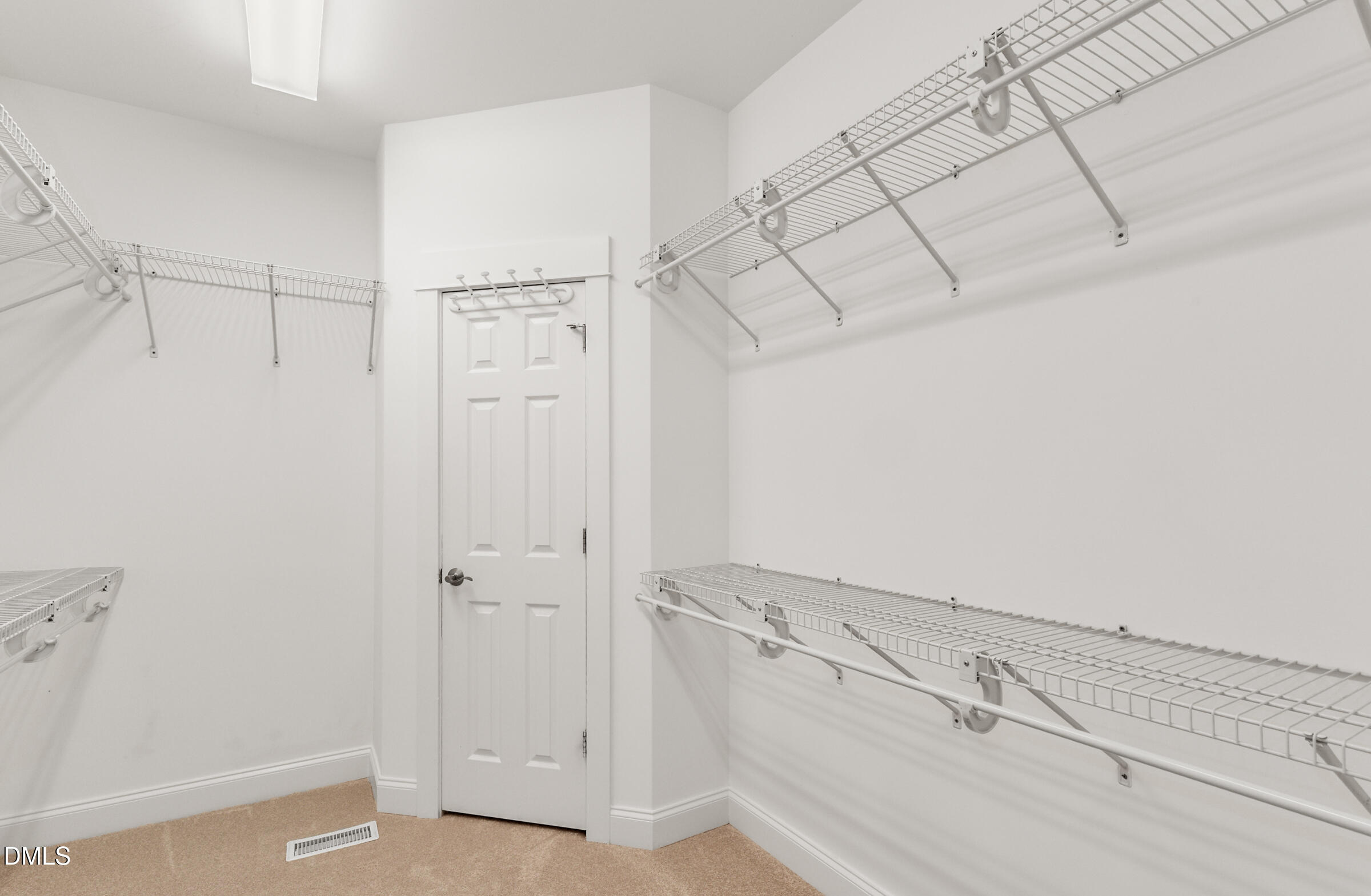 Walk-in closet with white wire shelving along three walls and a paneled door.