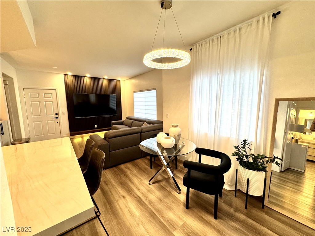 Living and dining area with a sectional sofa, dark slatted TV wall, glass table, and floor-to-ceiling curtains.