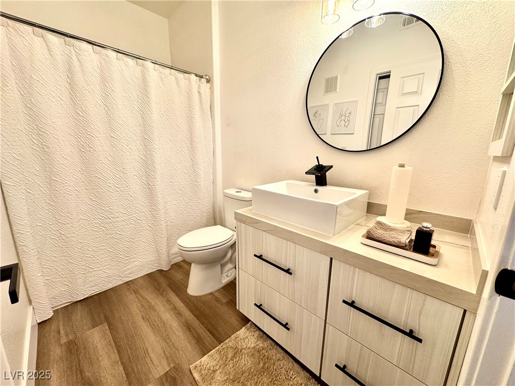 Bathroom with a light wood vanity, vessel sink, black faucet, and large round mirror.