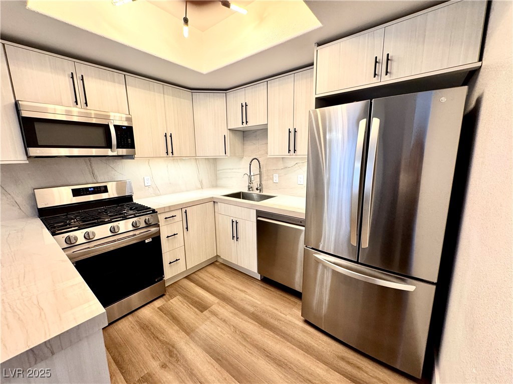 Renovated kitchen with light wood cabinets, stainless steel appliances, and a marble-look backsplash.
