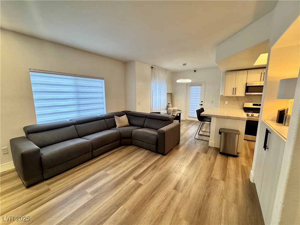 Open-plan living room with a dark gray sectional, wood-look floors, and kitchen island.
