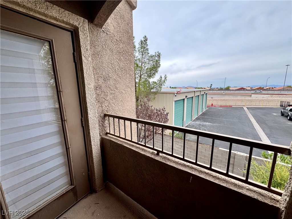 Covered apartment balcony overlooking a parking lot and storage units.