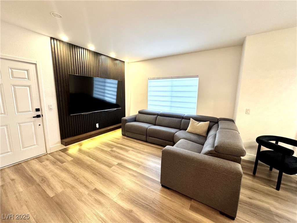 Living room with a gray sectional facing a television on a dark slatted accent wall.